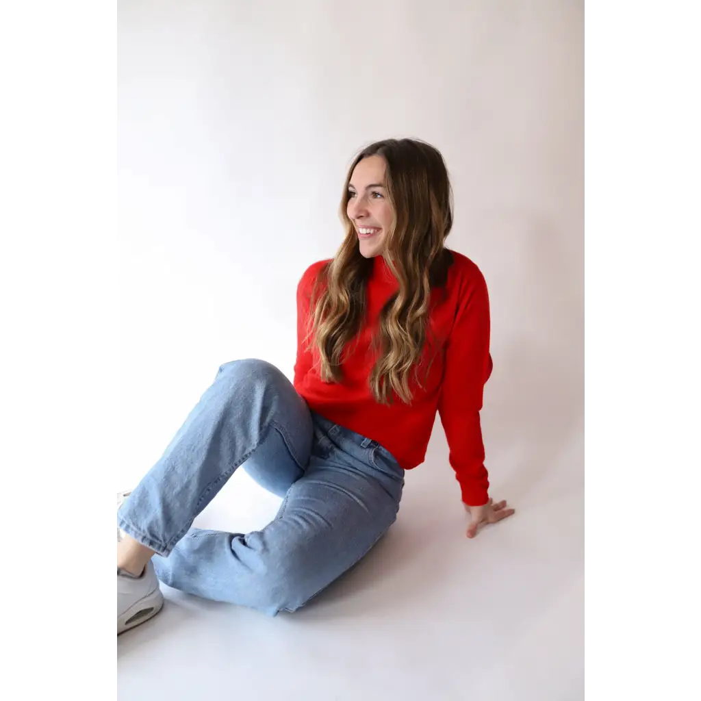 Person in bright red Sherry Sweater and light blue jeans, perfect for your everyday wardrobe