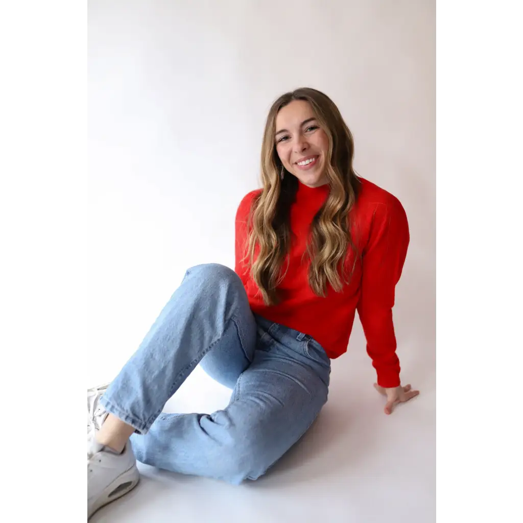 Person in a bright red Sherry Sweater and light blue jeans for your everyday wardrobe