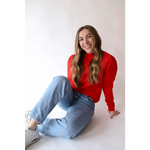 Person in a bright red Sherry Sweater and light blue jeans for your everyday wardrobe