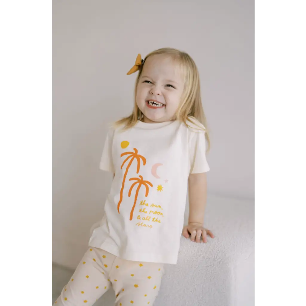 Joyful child in white t-shirt with orange palm trees, perfect for sun moon lovers!