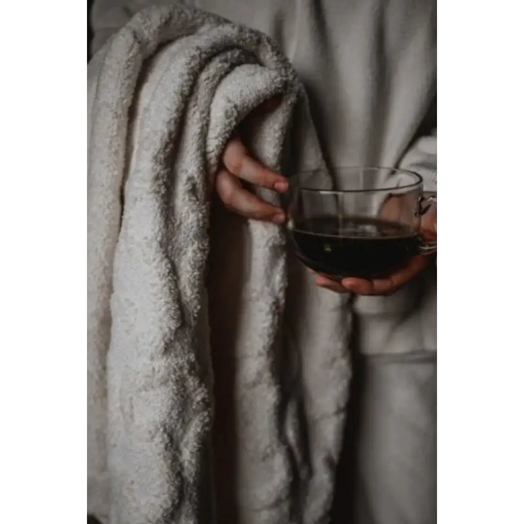 Hand holding red wine in cozy blanket with custom-made throw for warmest snuggles included