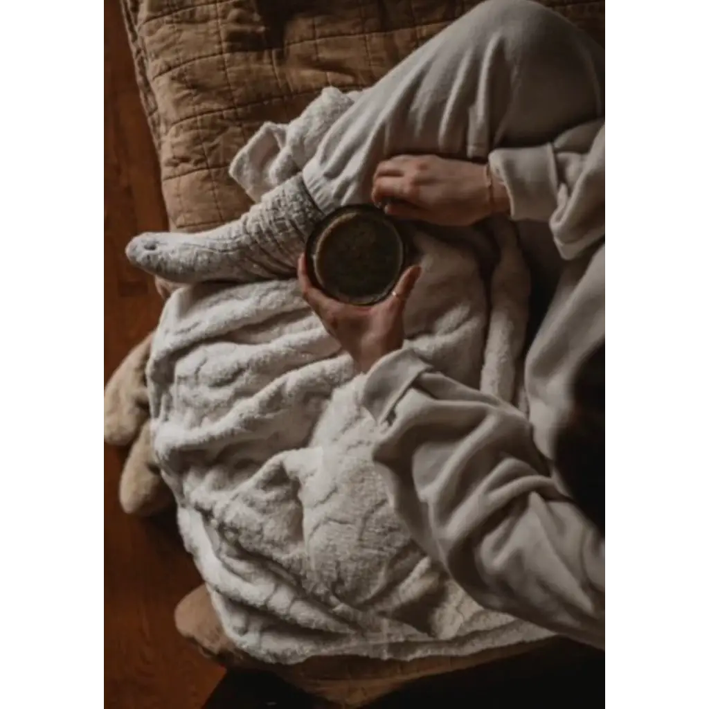 Cozy scene with wool socks, blanket, and coffee mug featuring warmest snuggles included