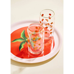 Two clear glass tumblers with fruit designs on a Tomato Gold Rimmed Soda Can Glass tray