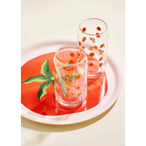 Two clear glass tumblers with fruit designs on a Tomato Gold Rimmed Soda Can Glass tray