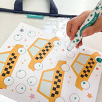 Kid hand uses green star dot marker on taxi eyes in Transportation activity kit