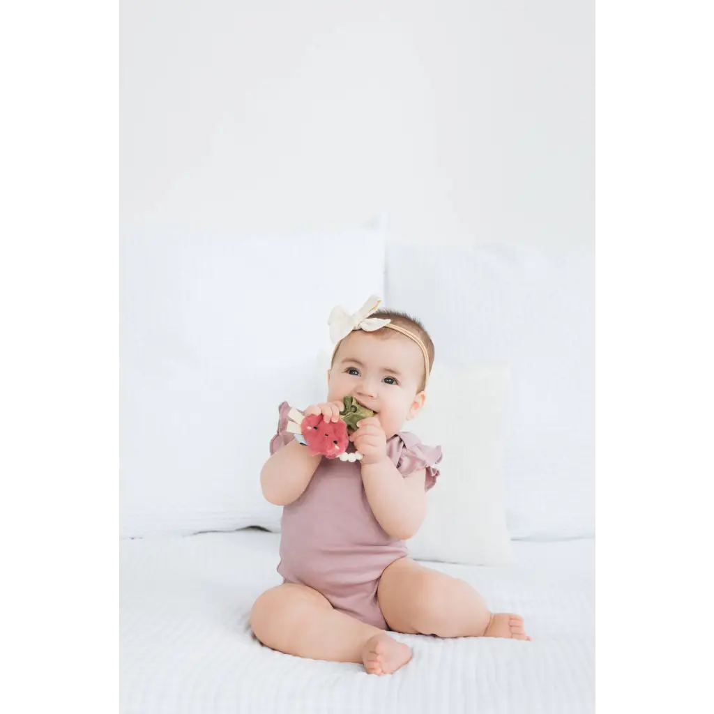 Lavender ruffled romper with bow detail on Turnip Crinkle Baby Teether