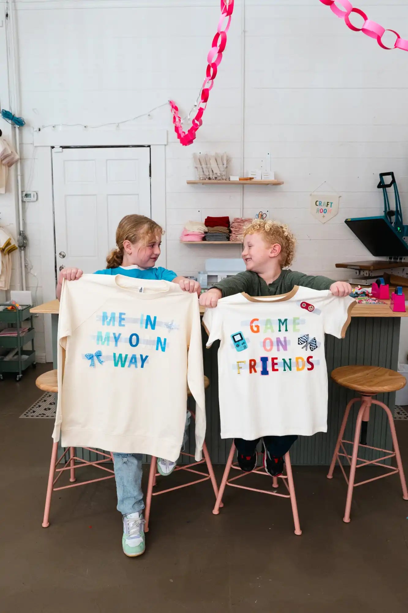 Two children holding up custom-designed shirts.