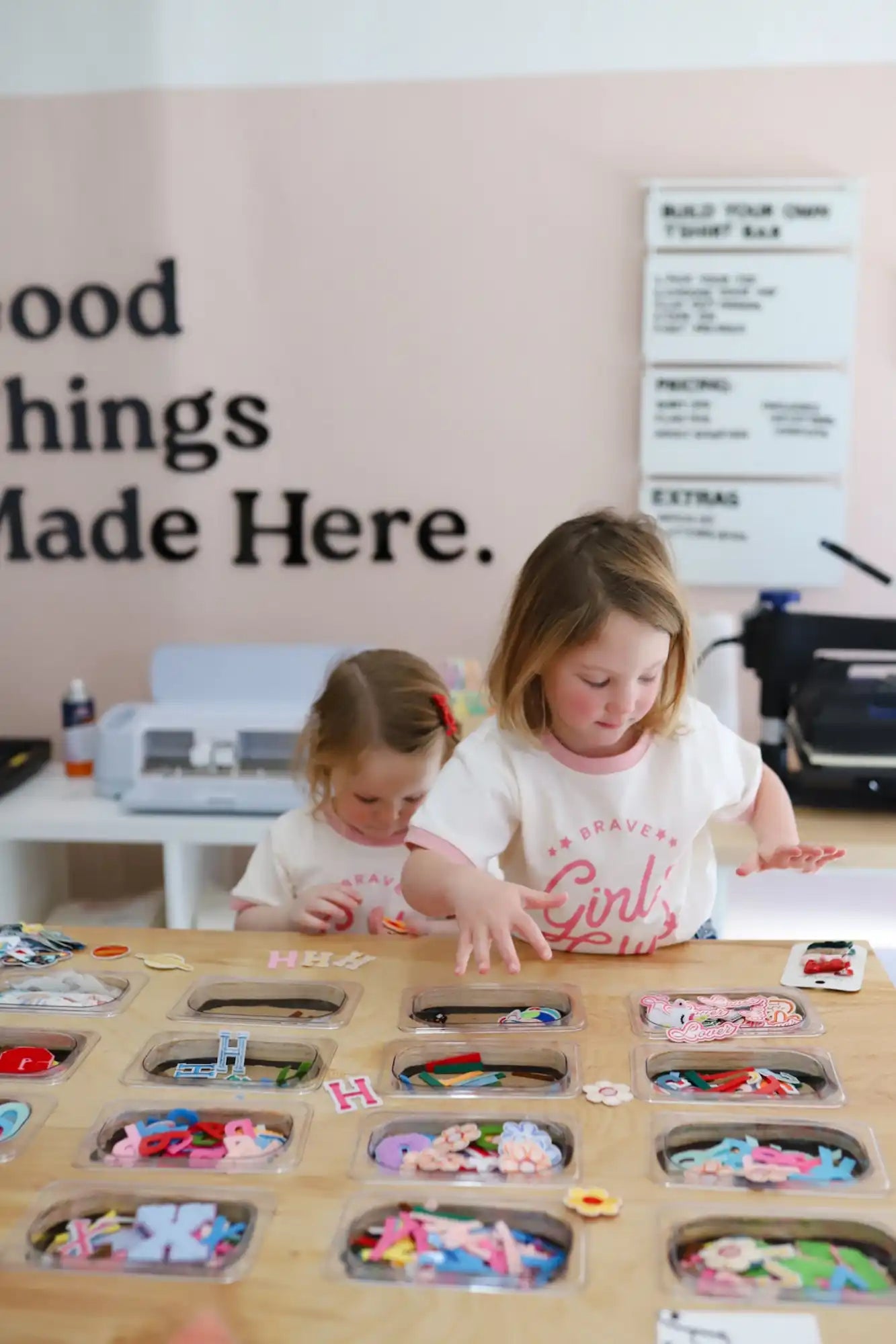 Two people working together at a wooden table with circular cutouts filled with colorful materials.