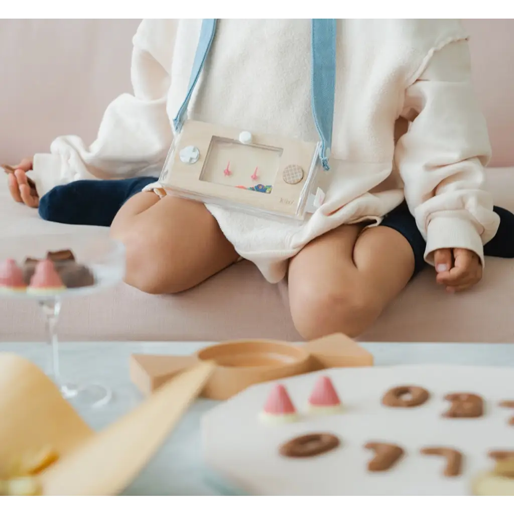 Baby in a white outfit with blue straps near cookies and Wakka Retro Water Game