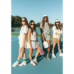 Four friends rocking Wave Wash Fleece Shorts on a tennis court for ultimate chill vibes