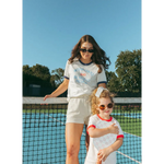 Two friends in matching white outfits by a tennis net rocking Wave Wash Fleece Shorts