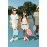 Three friends in Wave Wash Fleece shorts holding pickleball paddles on a sunny court