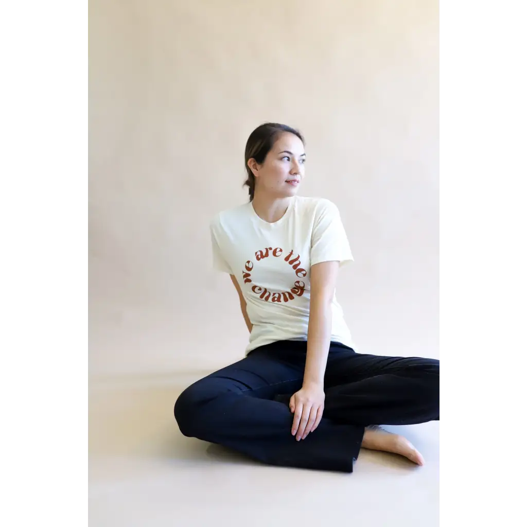 White Change Graphic T-shirt with circular design, styled with dark jeans in a relaxed pose