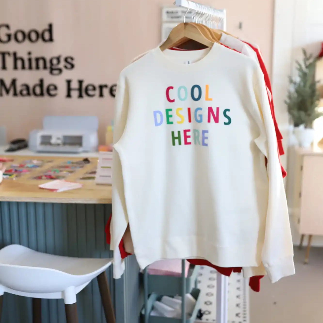 White sweatshirt with colorful text reading ’Cool Designs Here’