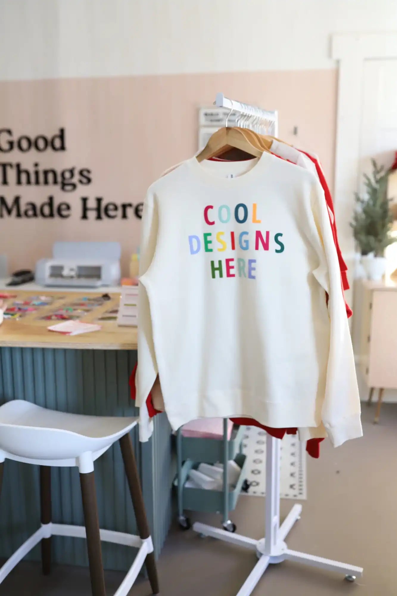White sweatshirt with colorful text reading ’Cool Designs Here’