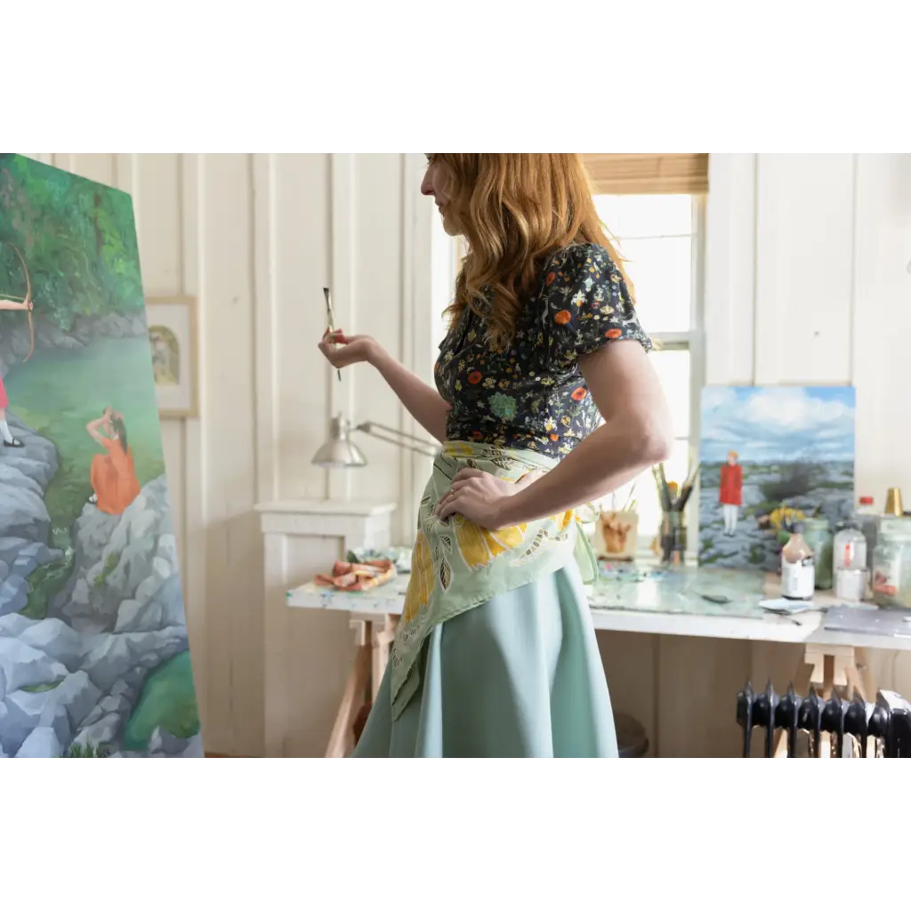 Artist in a floral top and mint skirt painting, featuring a 34x34 inches designed bandana