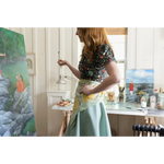 Artist in a floral top and mint skirt painting, featuring a 34x34 inches designed bandana