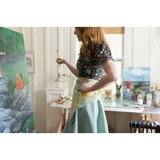 Artist in a floral top and mint skirt painting, featuring a 34x34 inches designed bandana