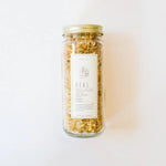 WildFlora bath salts jar with gold lid and dried golden herbs