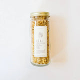WildFlora bath salts jar with gold lid and dried golden herbs