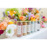 WildFlora bath salts in clear jars with colorful petals and beauty labels