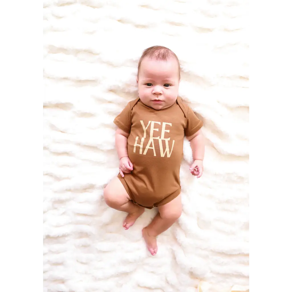Baby in a brown organic cotton bodysuit with YEE HAW for little cowboys and cowgirls